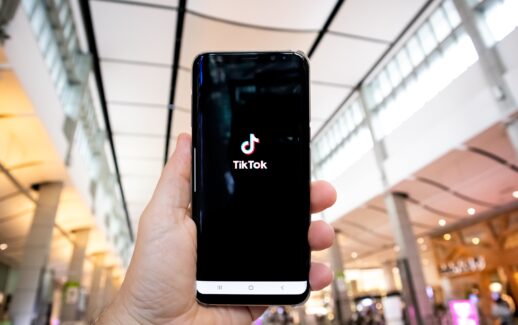 Mão segurando um celular com o aplicativo TikTok na tela
