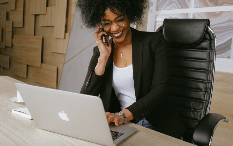 mulher empresária negra sorrindo sentada trabalhando