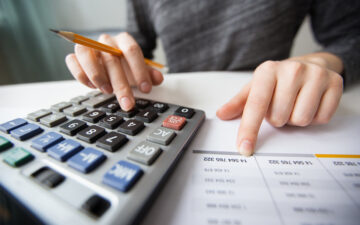 Close de uma pessoa usando a calculadora para calcular os impostos da Reforma Tributária.