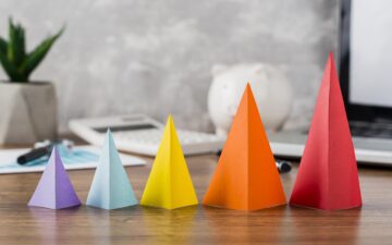 Cones de cores e tamanhos diferentes empilhados em ordem crescente da esquerda para a direita, simulando um funil de vendas.