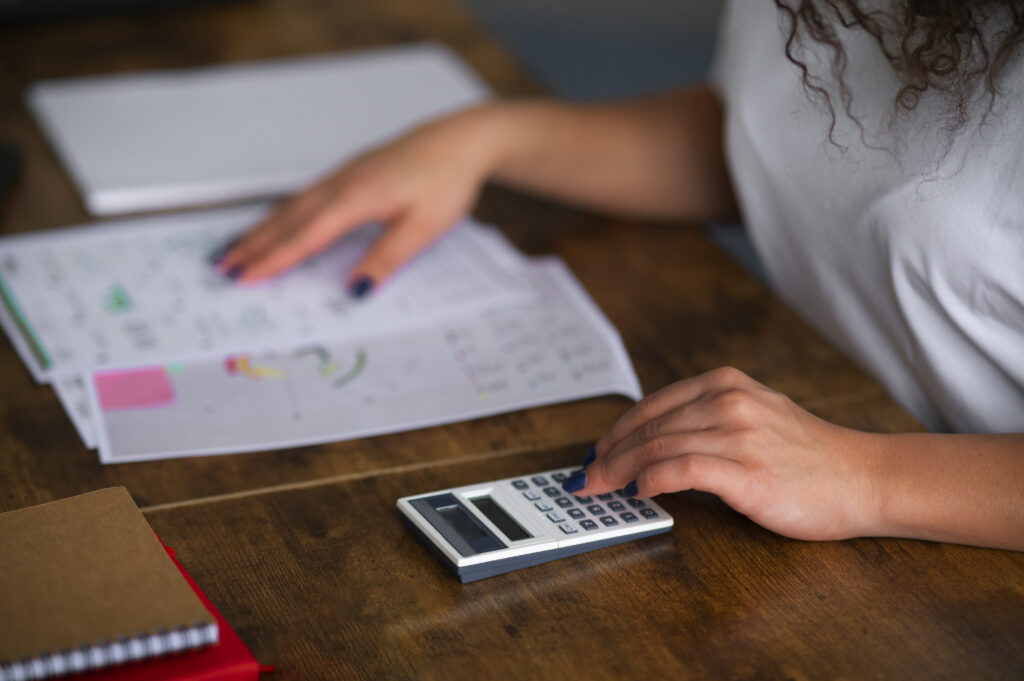 Mulher calculando suas contas para evitar inadimplência no fim de ano.